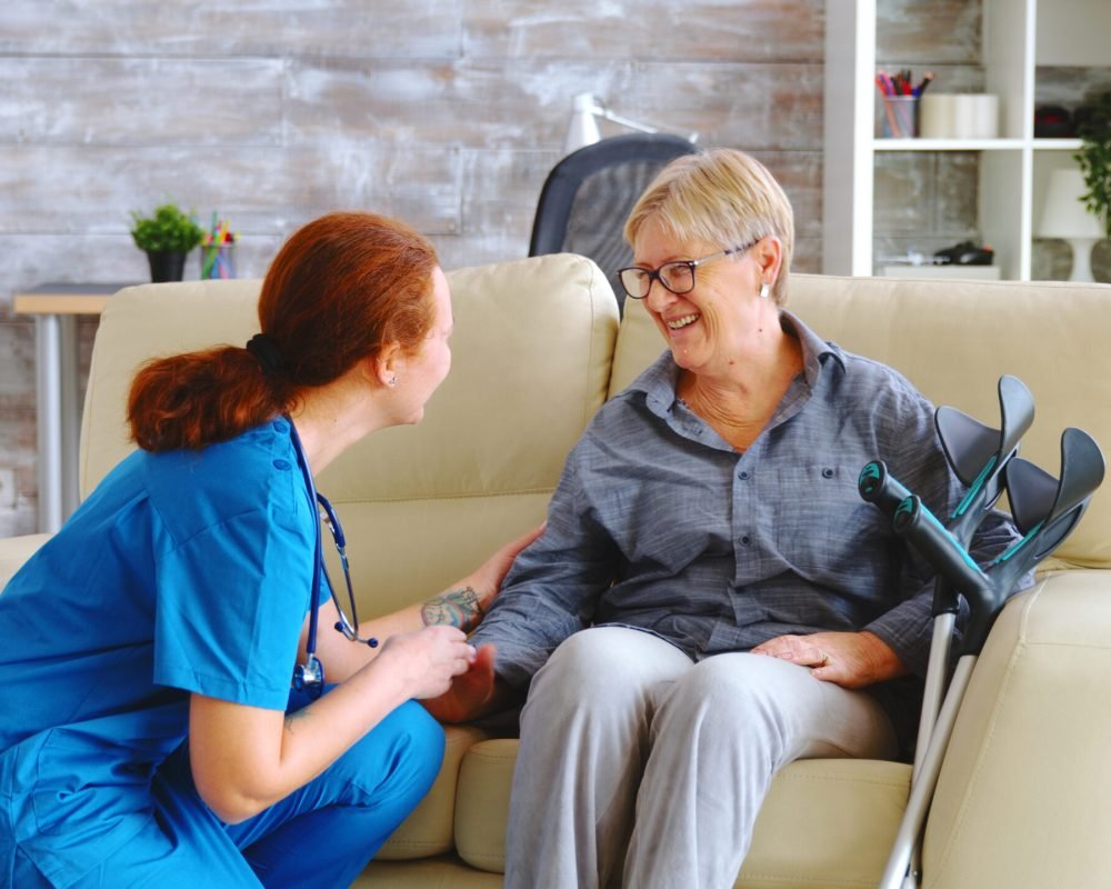 Female nurse talking with old woman with alzheimer in nursing home
